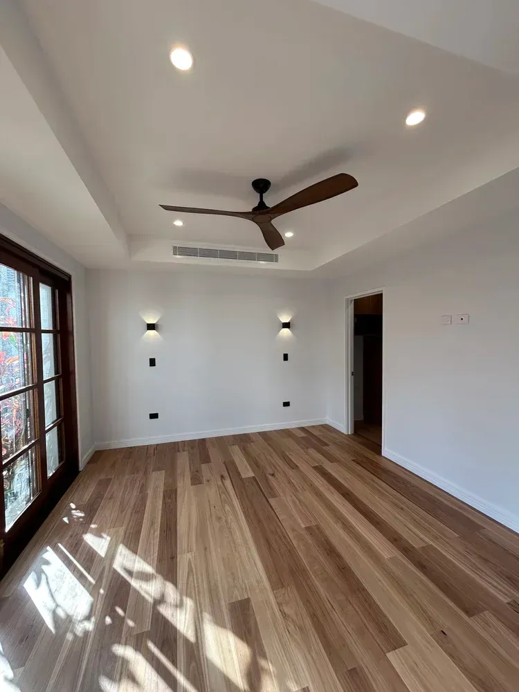 A Minimalist Empty Bedroom With Light Wood Flooring — BTM Electrical & Air in Southport, QLD