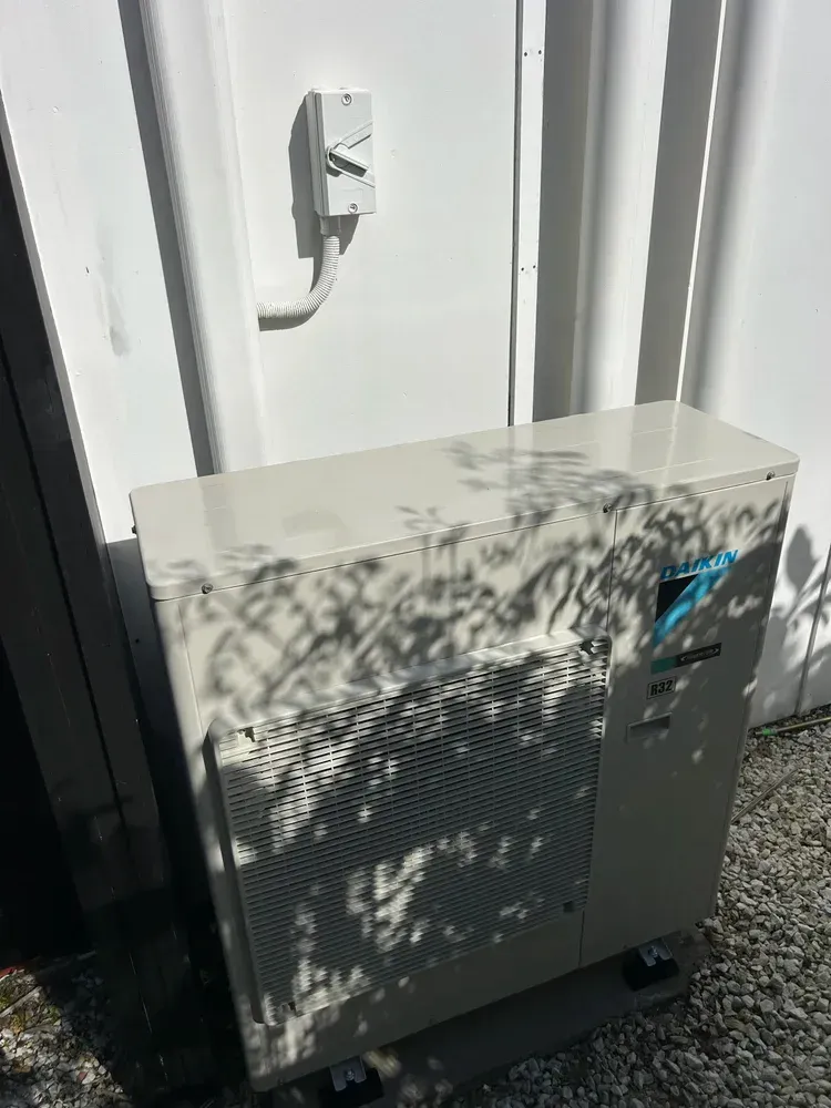 An Outdoor Daikin Heat Pump Unit With an Electrical Disconnect Switch — BTM Electrical & Air in Palm Beach, QLD
