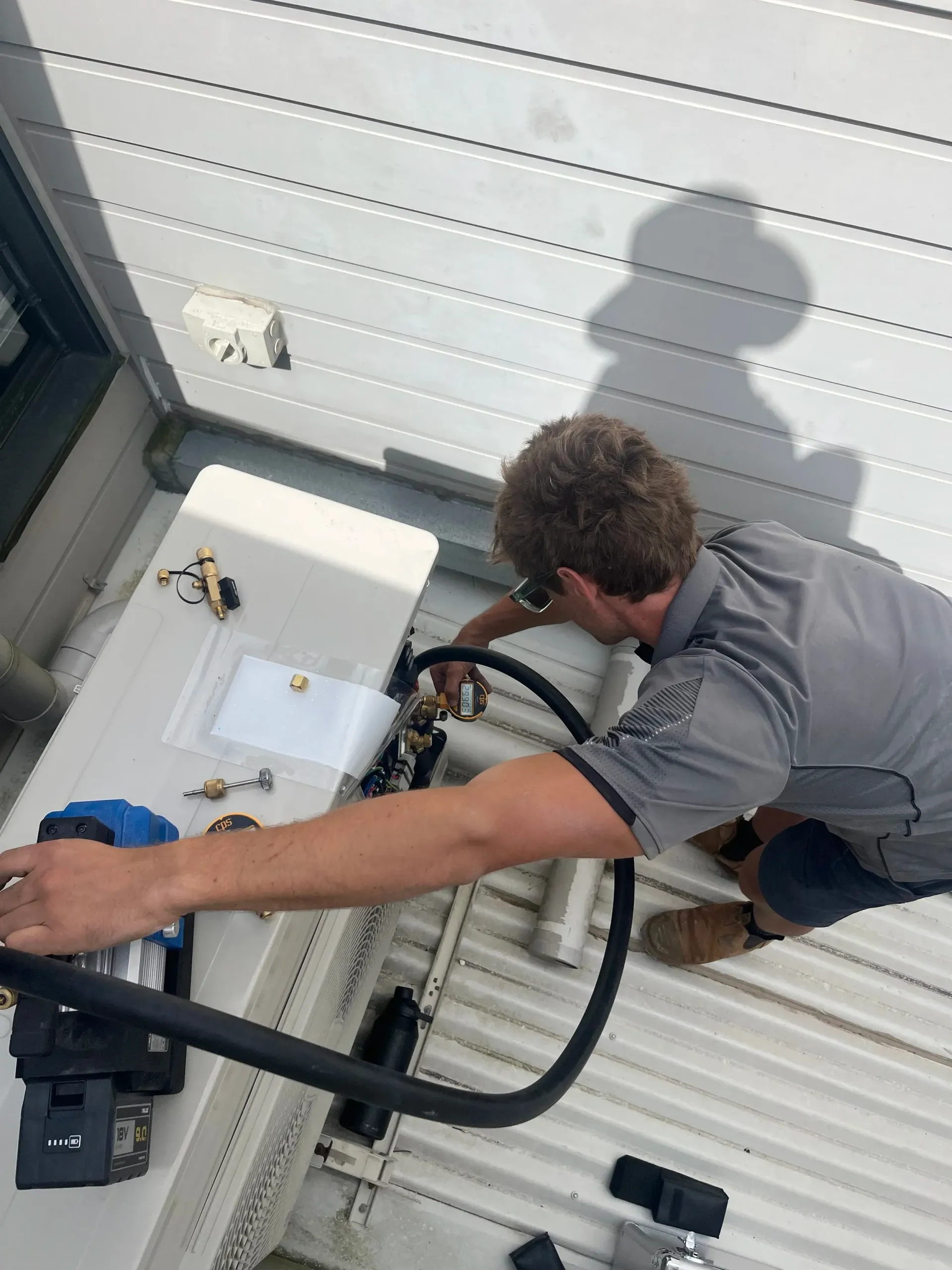 Man Working on the Components of an Outdoor Air Conditioning Unit — BTM Electrical & Air in Burleigh Waters, QLD