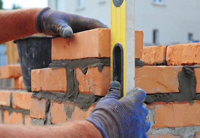 Bricklayer using a spirit level on a new brick wall.