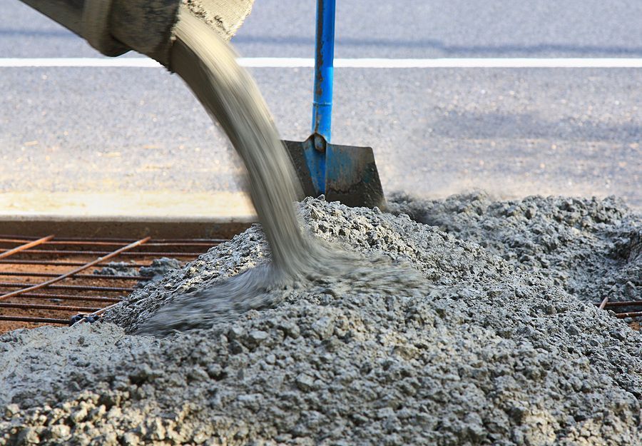 Wet concrete pouring onto rebar at a construction site.