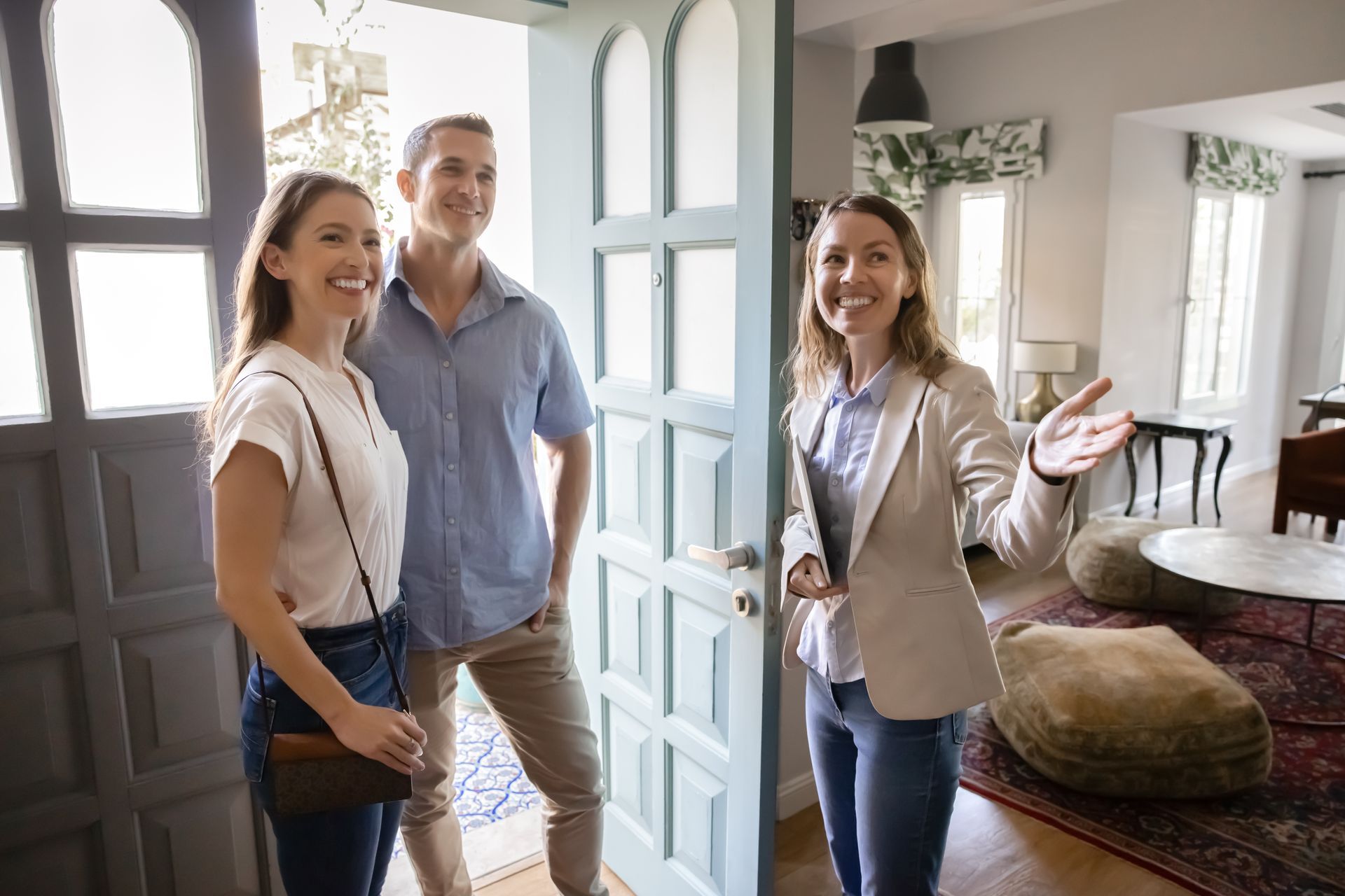 Real estate agent welcomes a couple into a home. They are smiling. Real estate agent welcomes a couple into a home. They are smiling.