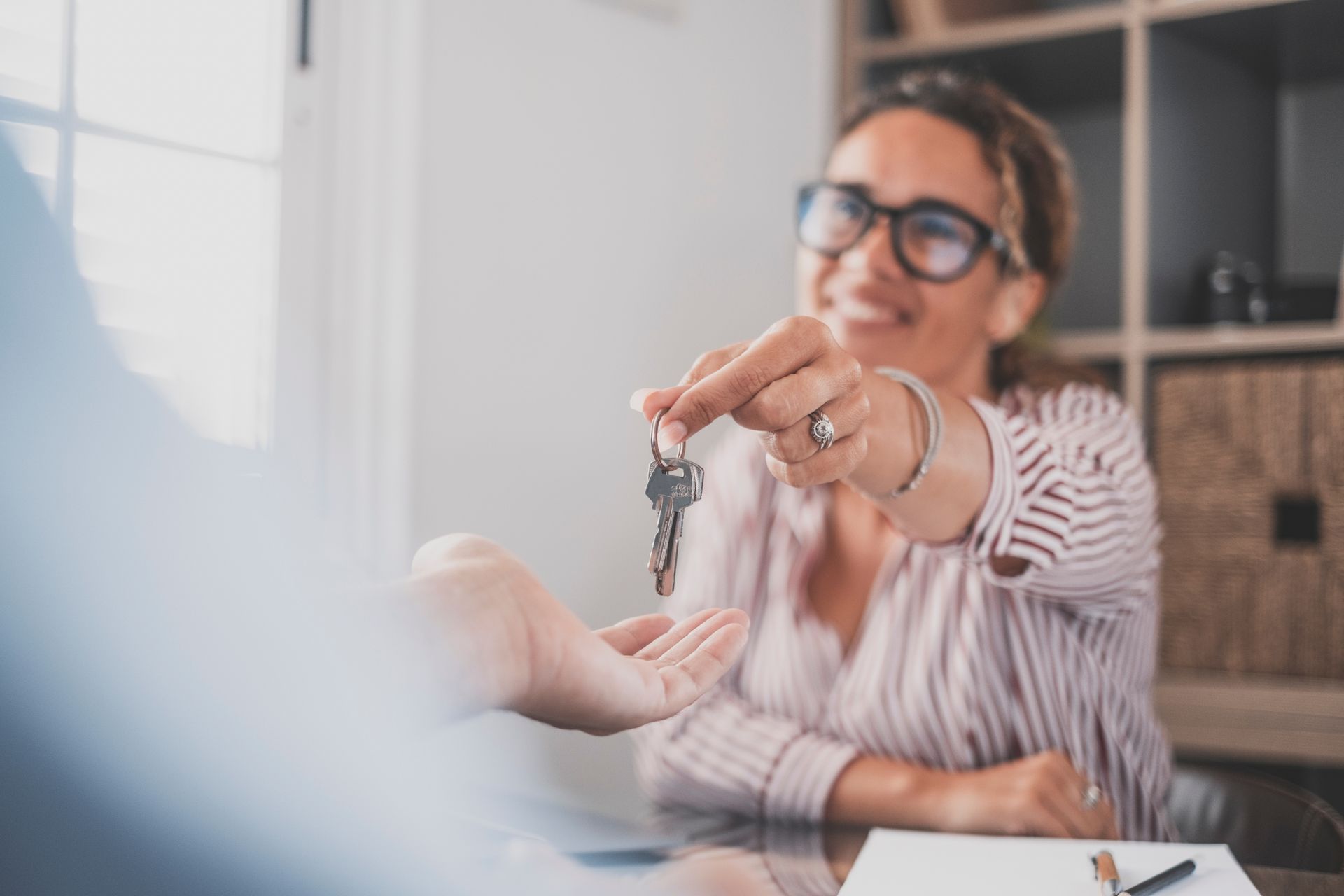 Person handing keys to another person. Smiling, indoors, likely a real estate transaction. Person handing keys to another person. Smiling, indoors, likely a real estate transaction.