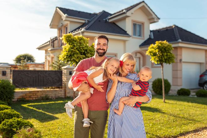 Family of four smiling in front of their house. Family of four smiling in front of their house.