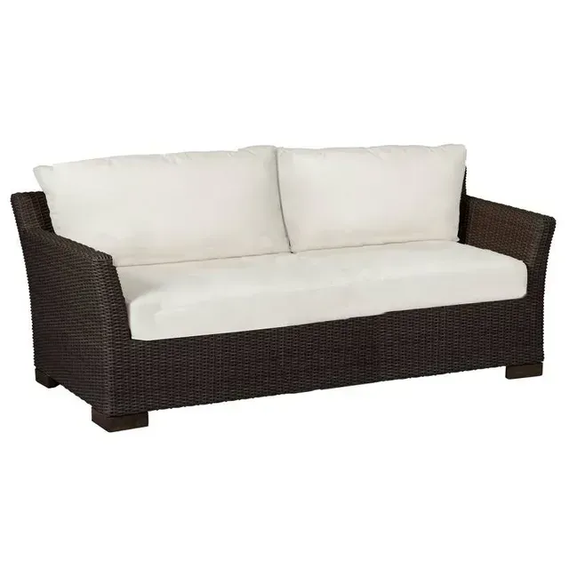 Brown wicker outdoor sofa with white cushions.