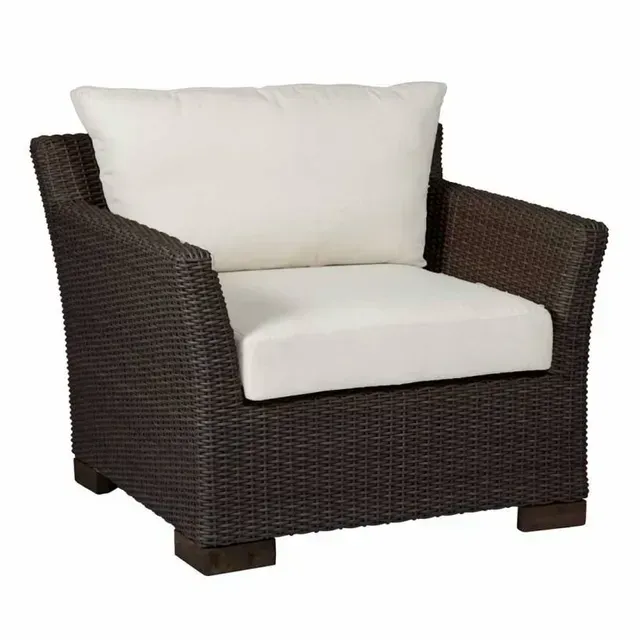 Brown wicker outdoor armchair with white cushions.