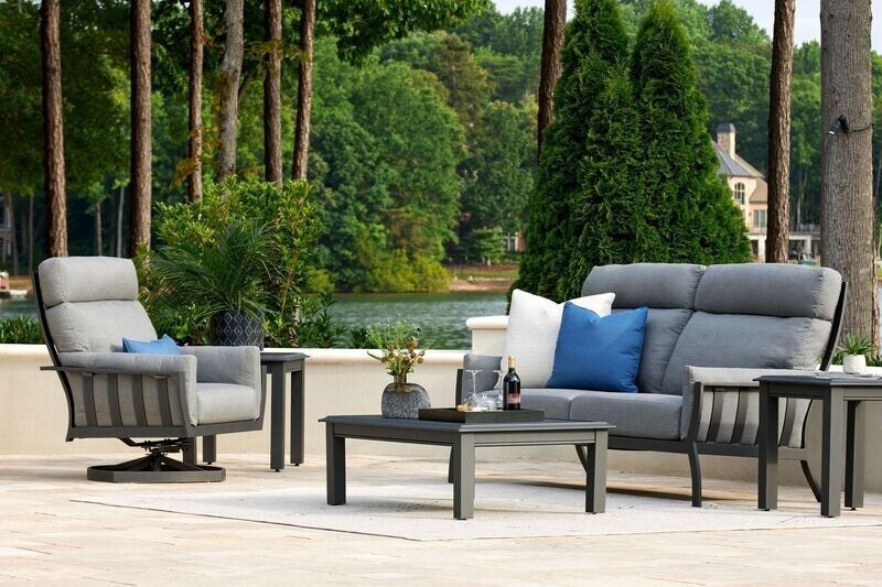 Outdoor patio furniture set in gray with lake and trees in background.