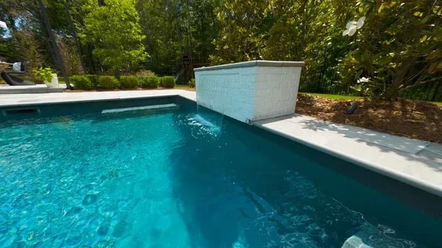 Swimming pool with a turquoise blue color and white deck in a sunny, outdoor setting.