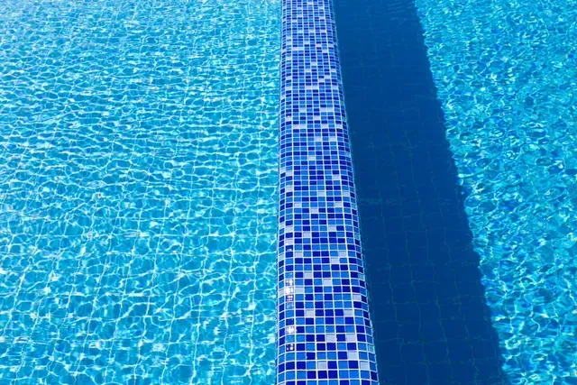 Close-up of a swimming pool with a blue tile border separating the shallow and deep ends.