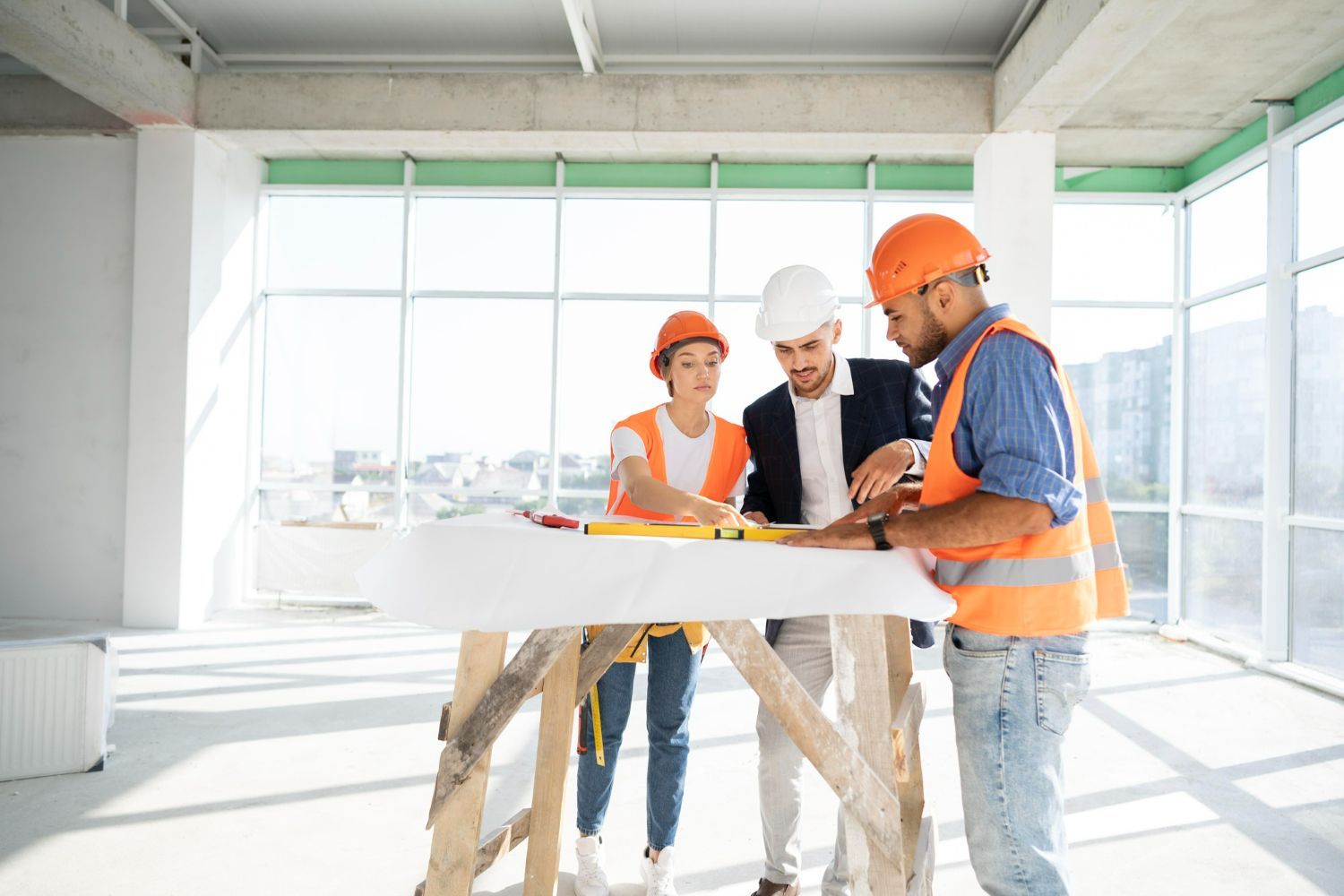 A group of construction workers are standing around a table looking at a blueprint.