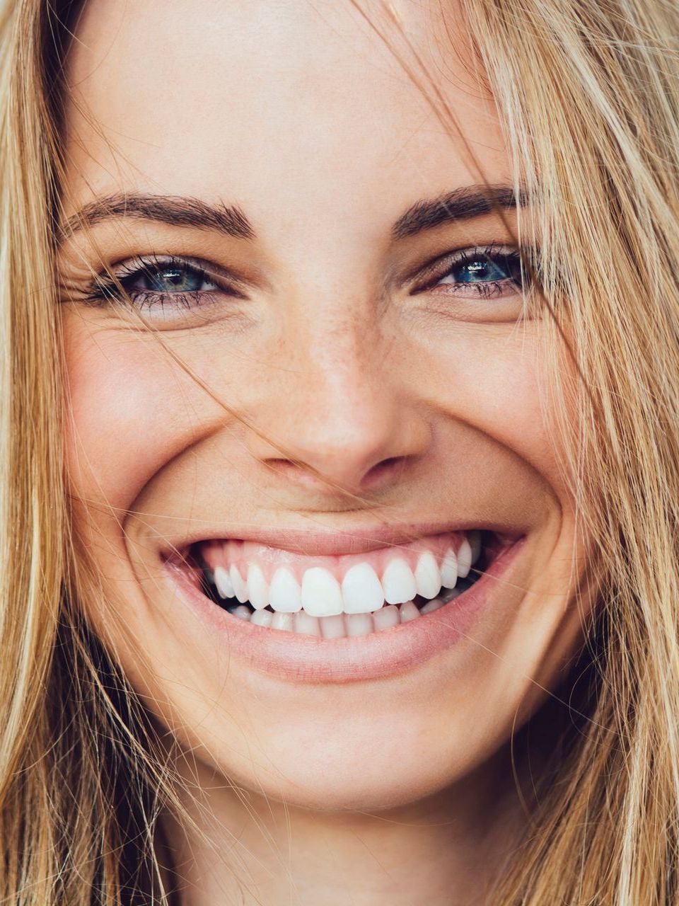 A close up of a woman 's face with a big smile on her face.