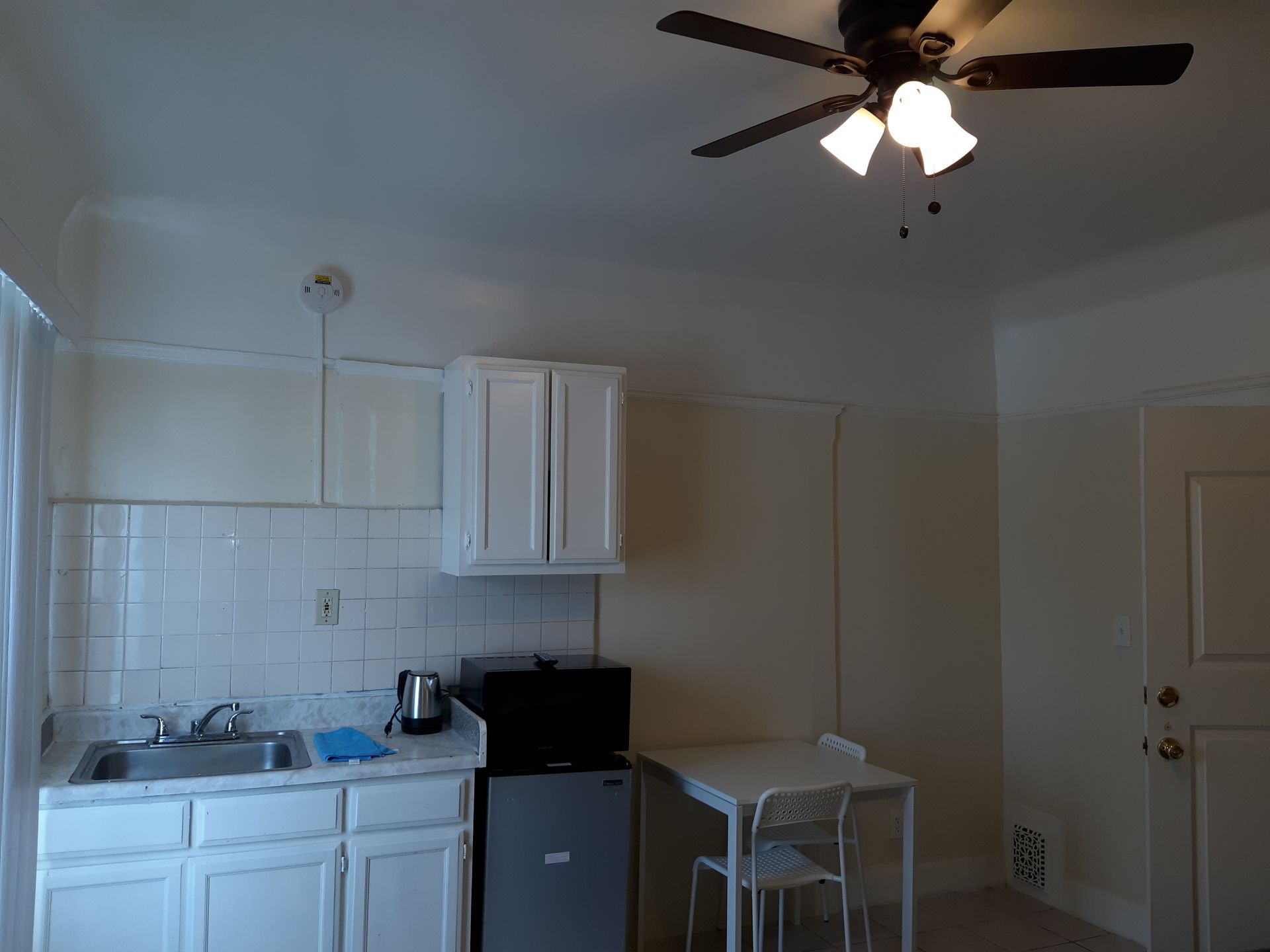 A kitchen with white cabinets and a ceiling fan
