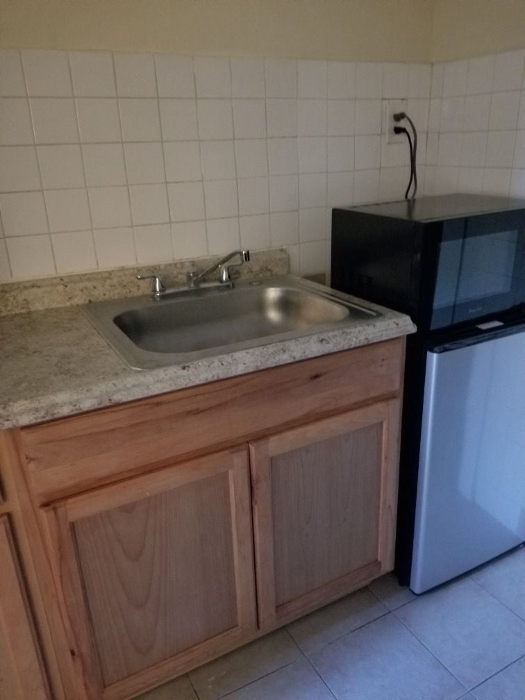 A kitchen with a sink a microwave and a refrigerator