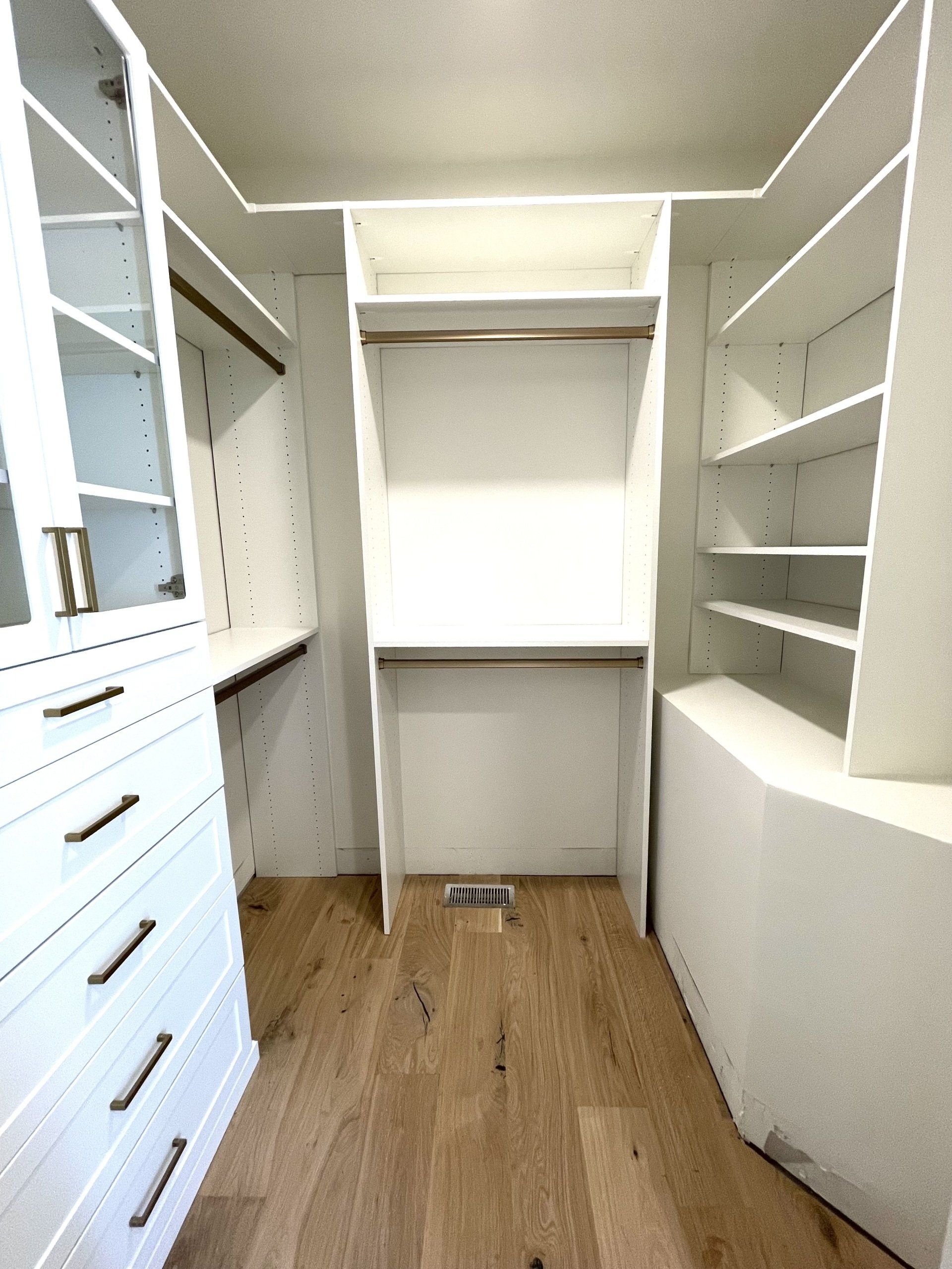 A walk in closet with lots of shelves and drawers