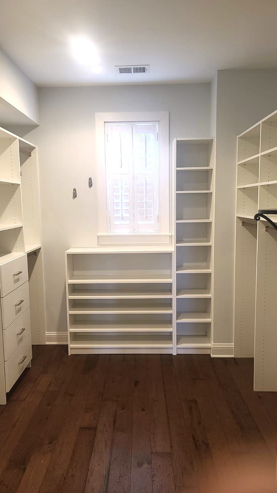 A walk in closet with lots of shelves and a window.