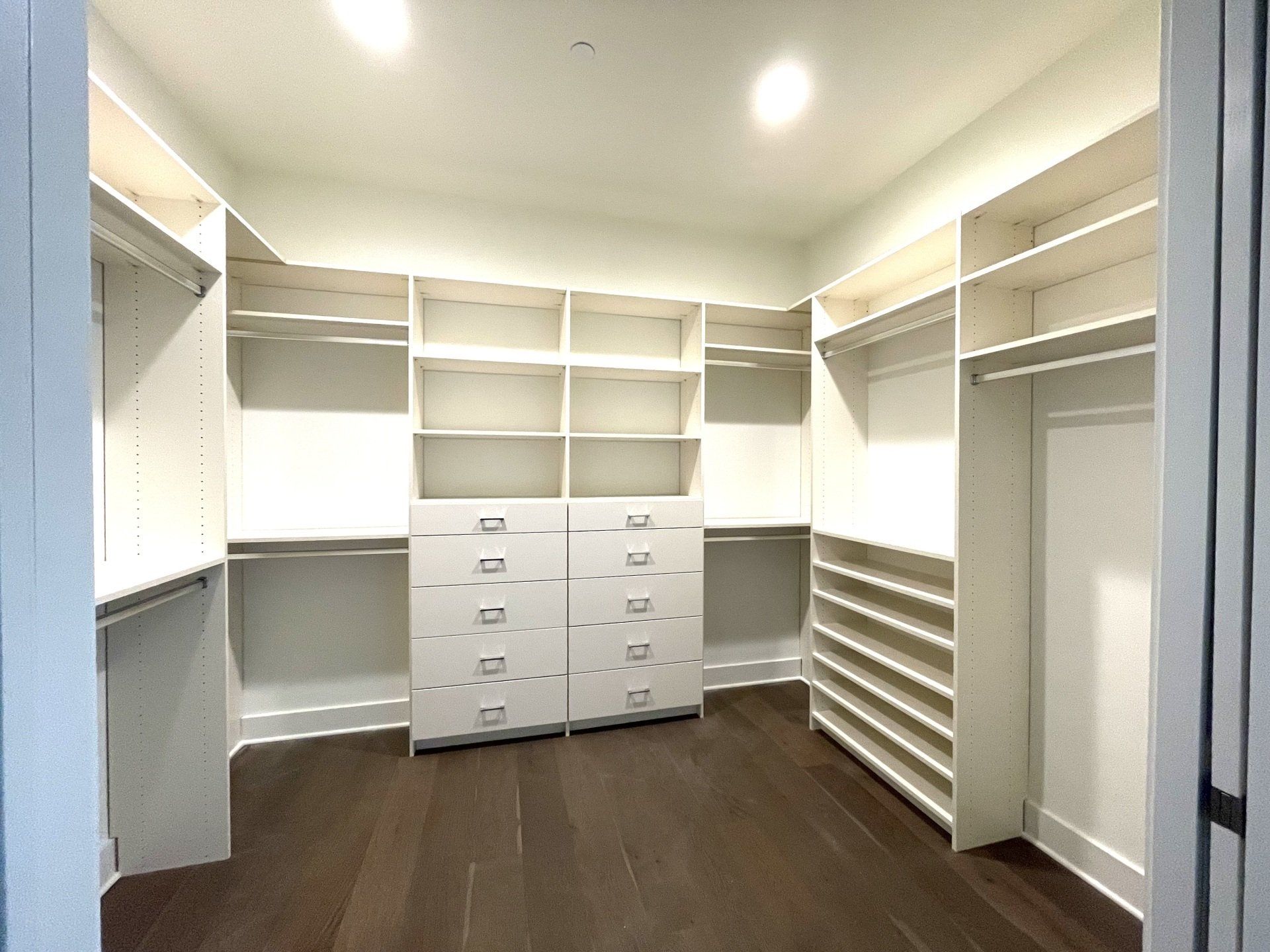 A walk in closet with lots of shelves and drawers