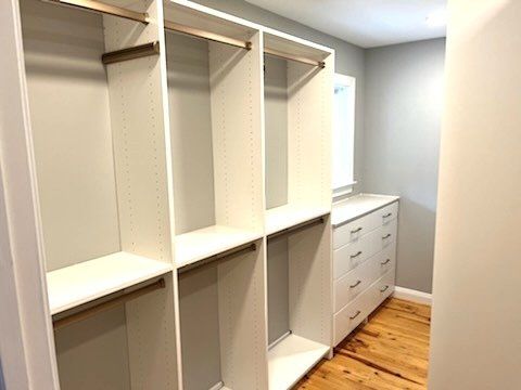 A walk in closet with lots of shelves and drawers.