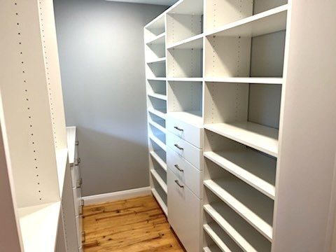 A walk in closet with lots of shelves and drawers.