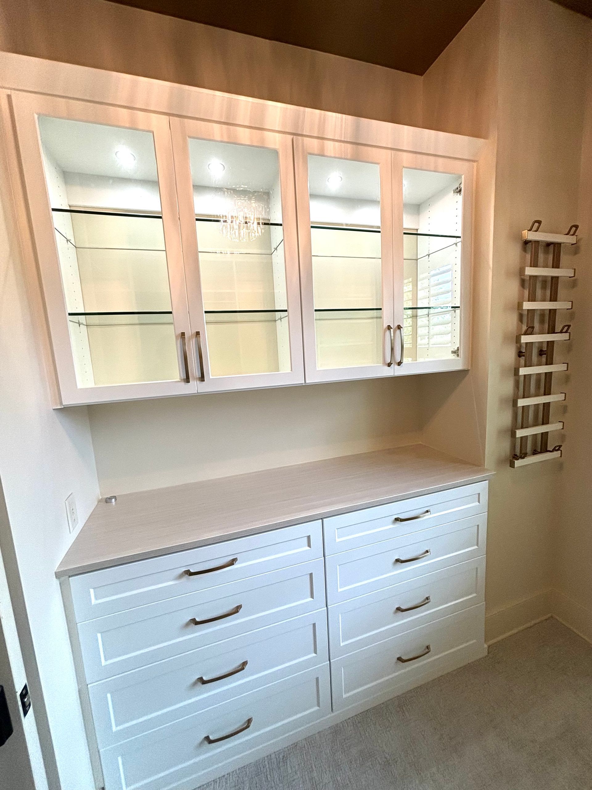 A white cabinet with glass doors and drawers in a room.