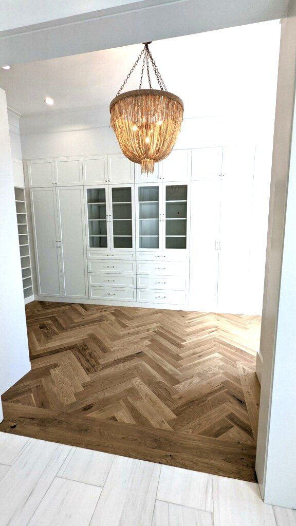 A room with a wooden floor and a chandelier hanging from the ceiling.