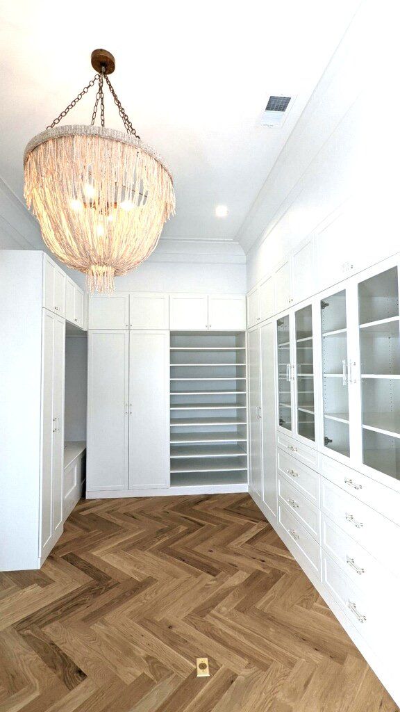 A large walk in closet with a chandelier hanging from the ceiling.