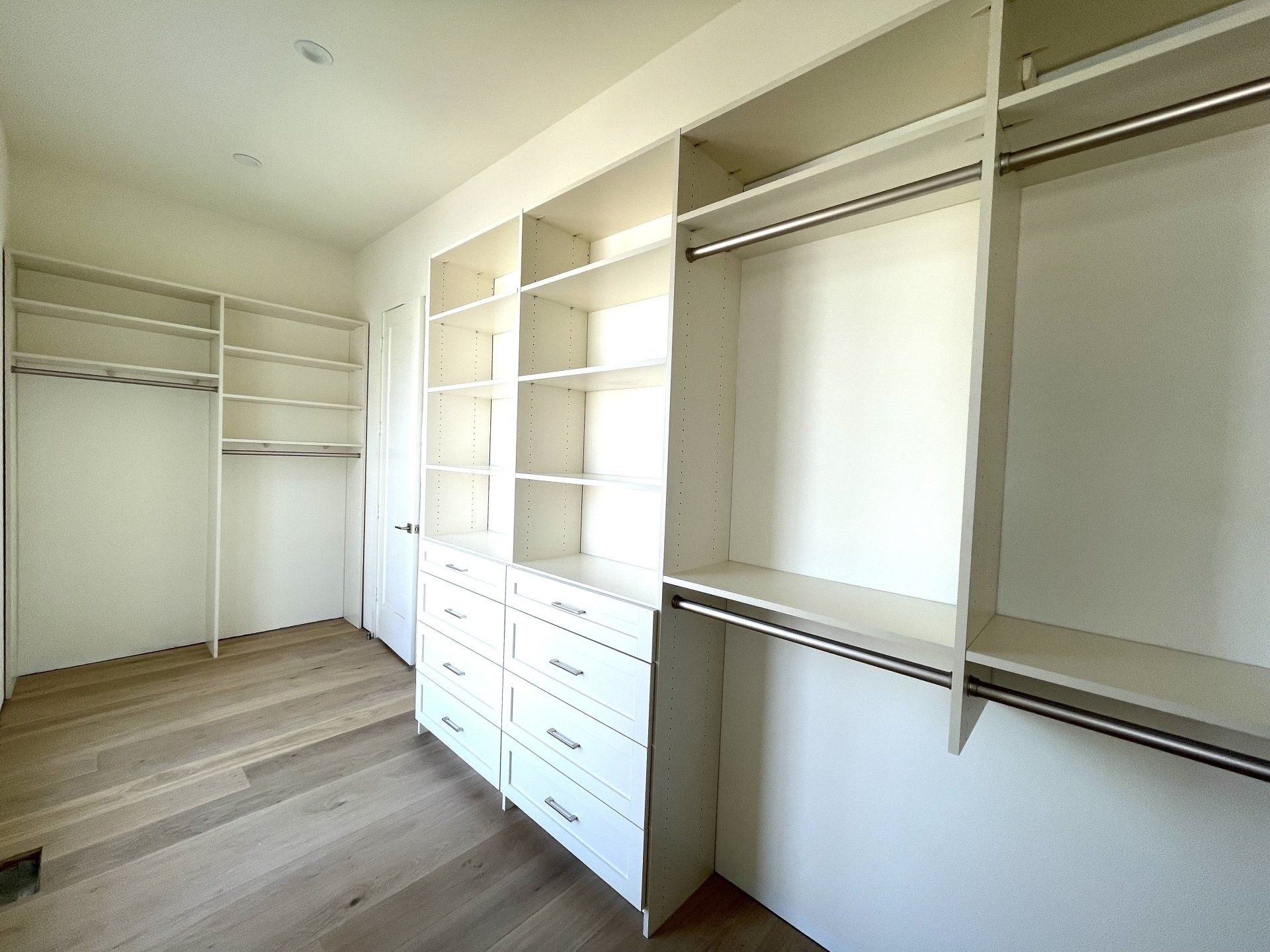 A walk in closet with lots of shelves and drawers.