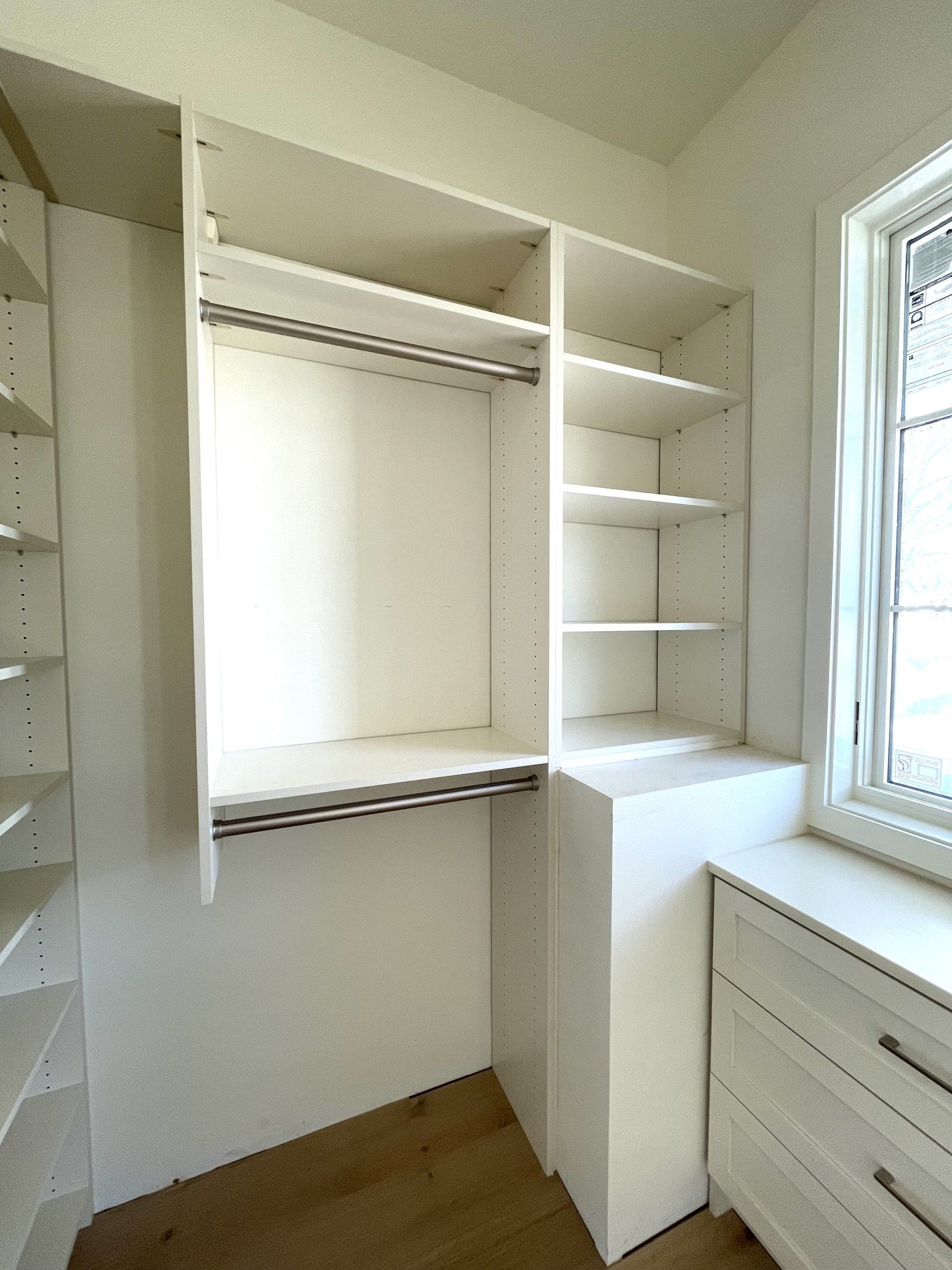A walk in closet with lots of shelves and a window.