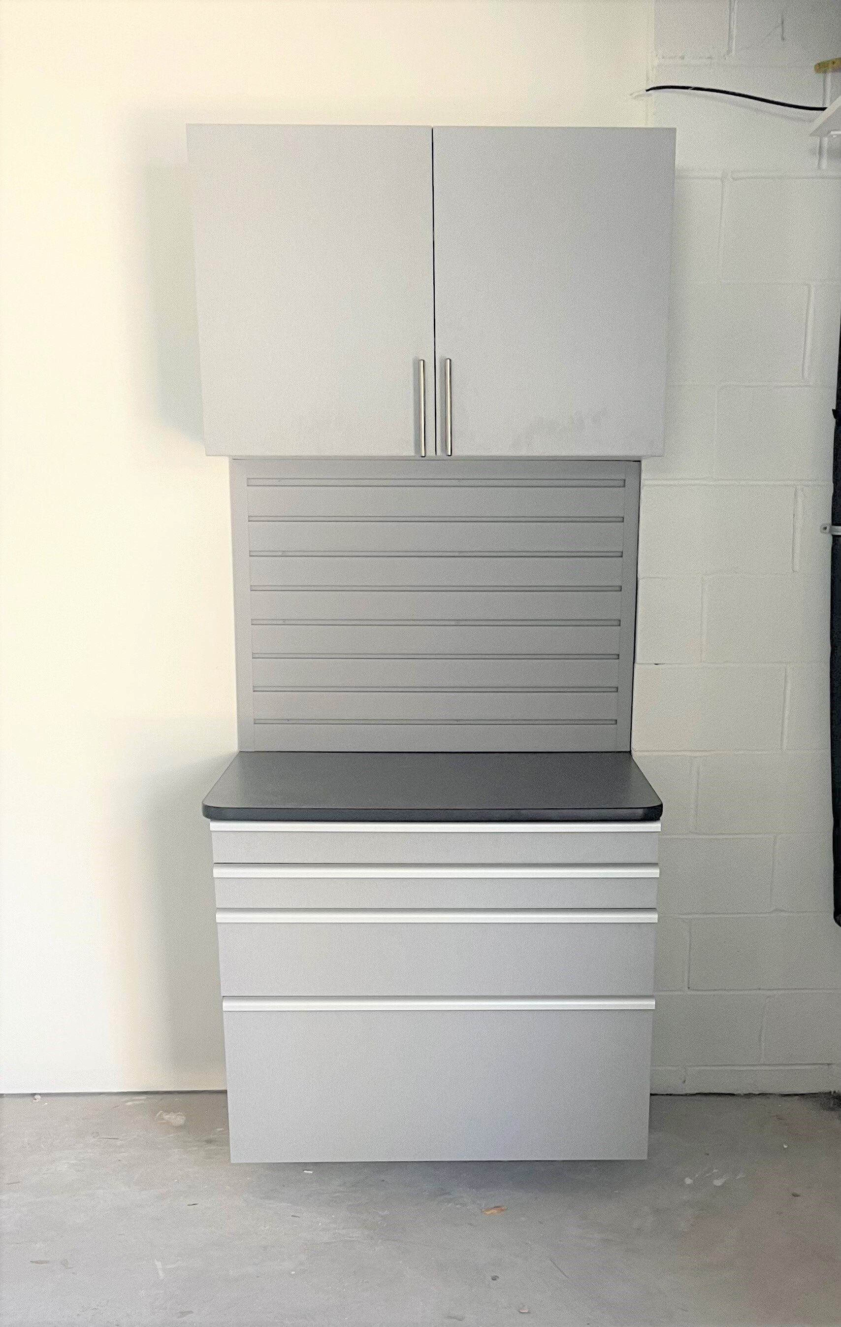 A gray cabinet with drawers and a black counter top in a garage.
