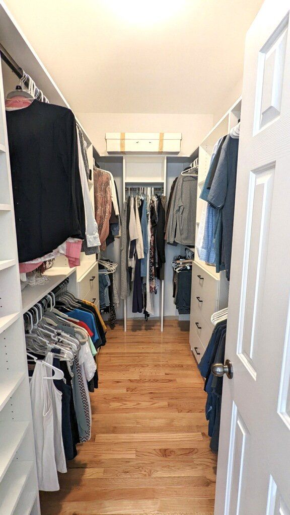 A walk in closet filled with lots of clothes and a door open.