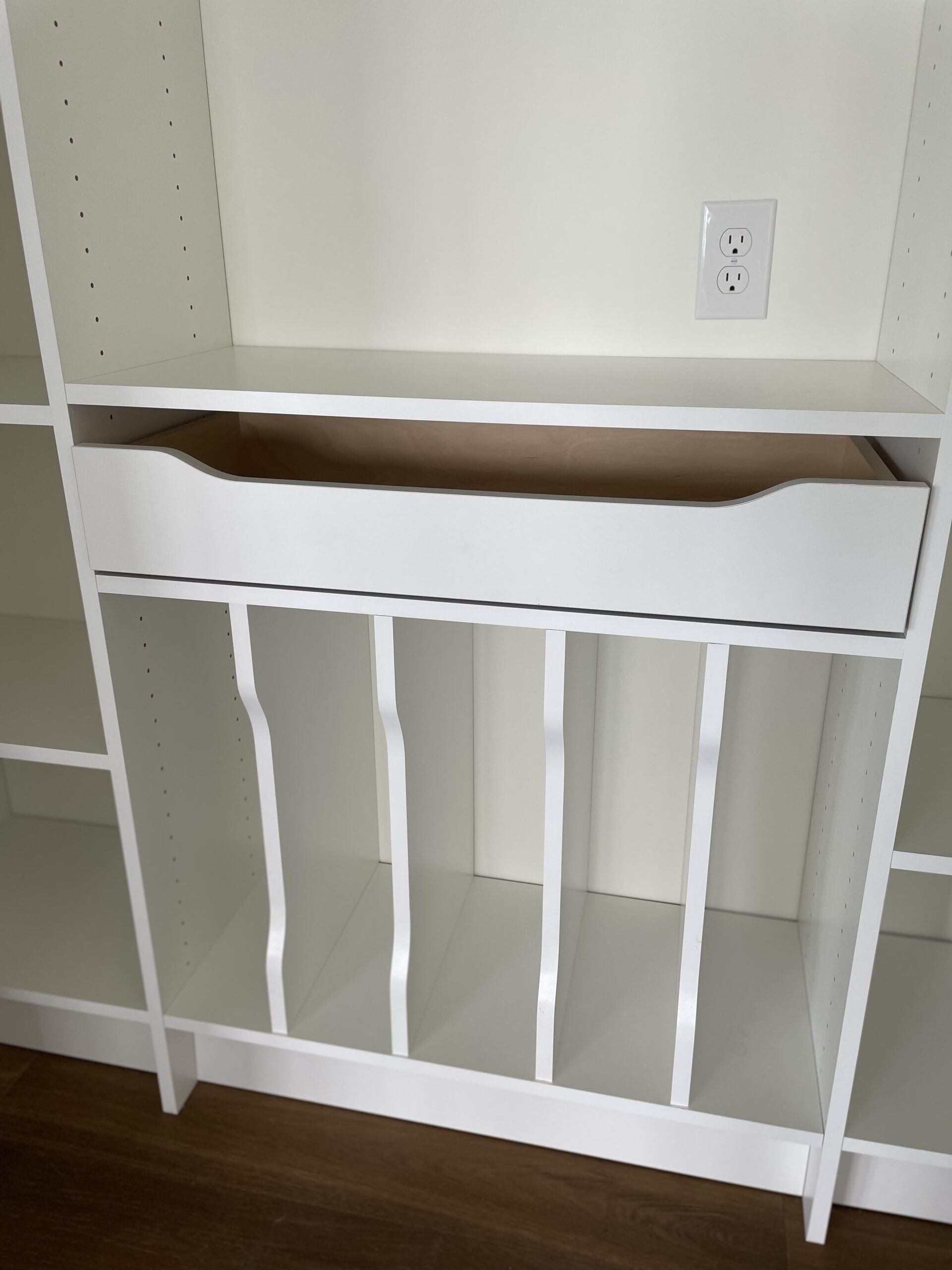 A white shelf with a drawer underneath it