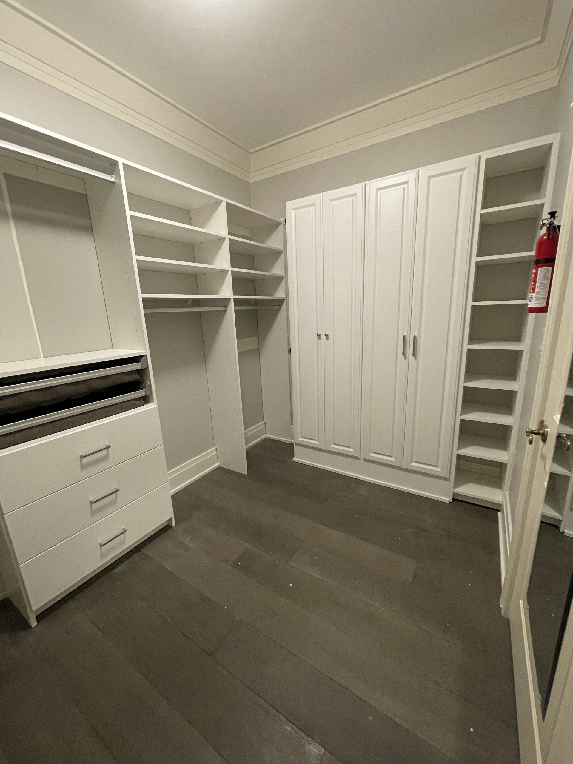 A large walk in closet with lots of shelves and drawers.