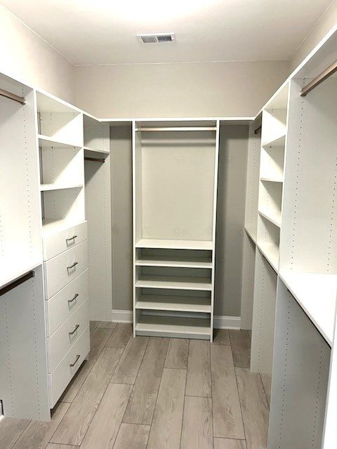 A walk in closet with lots of shelves and drawers.