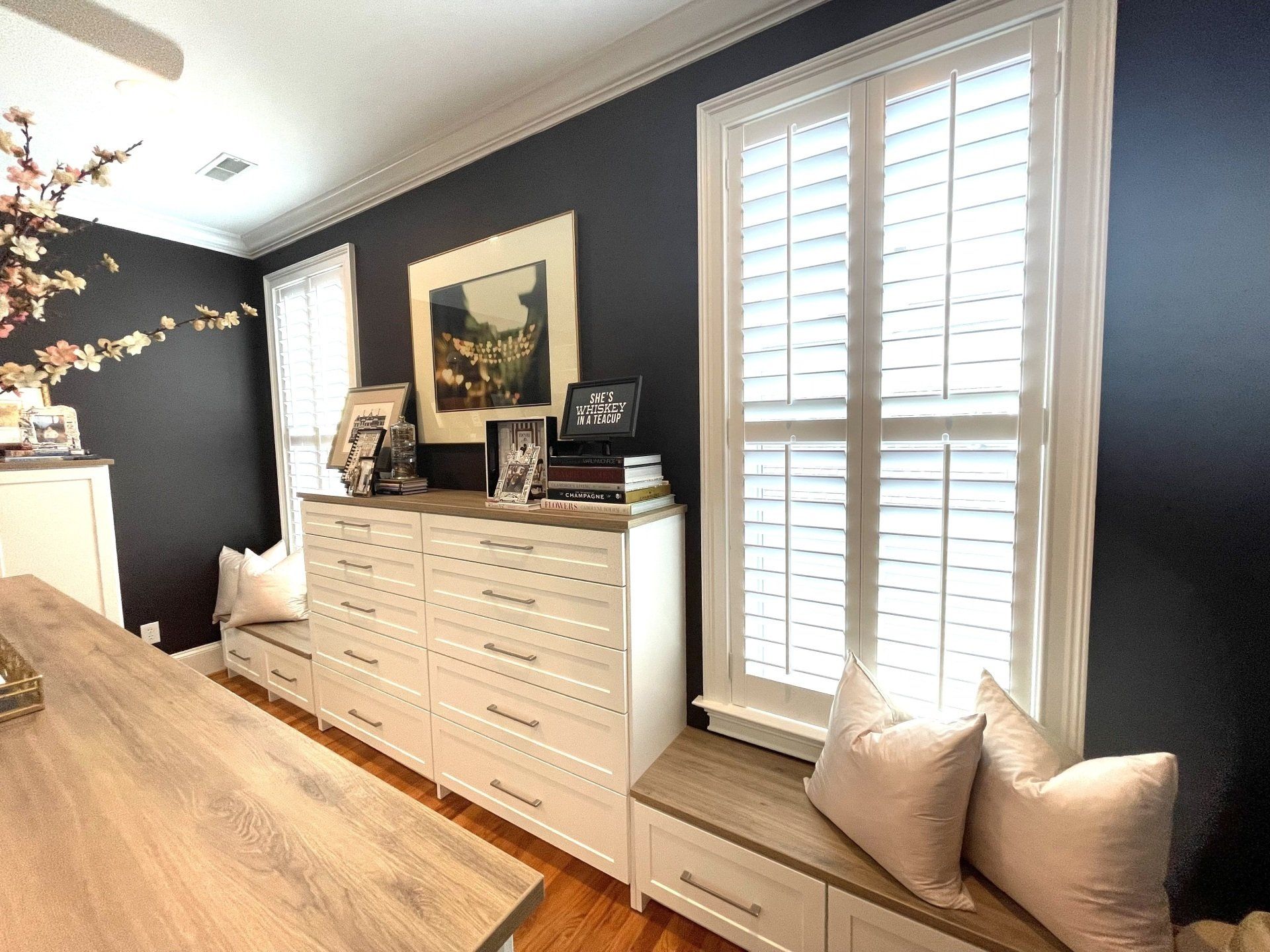 A room with a dresser and a window with shutters