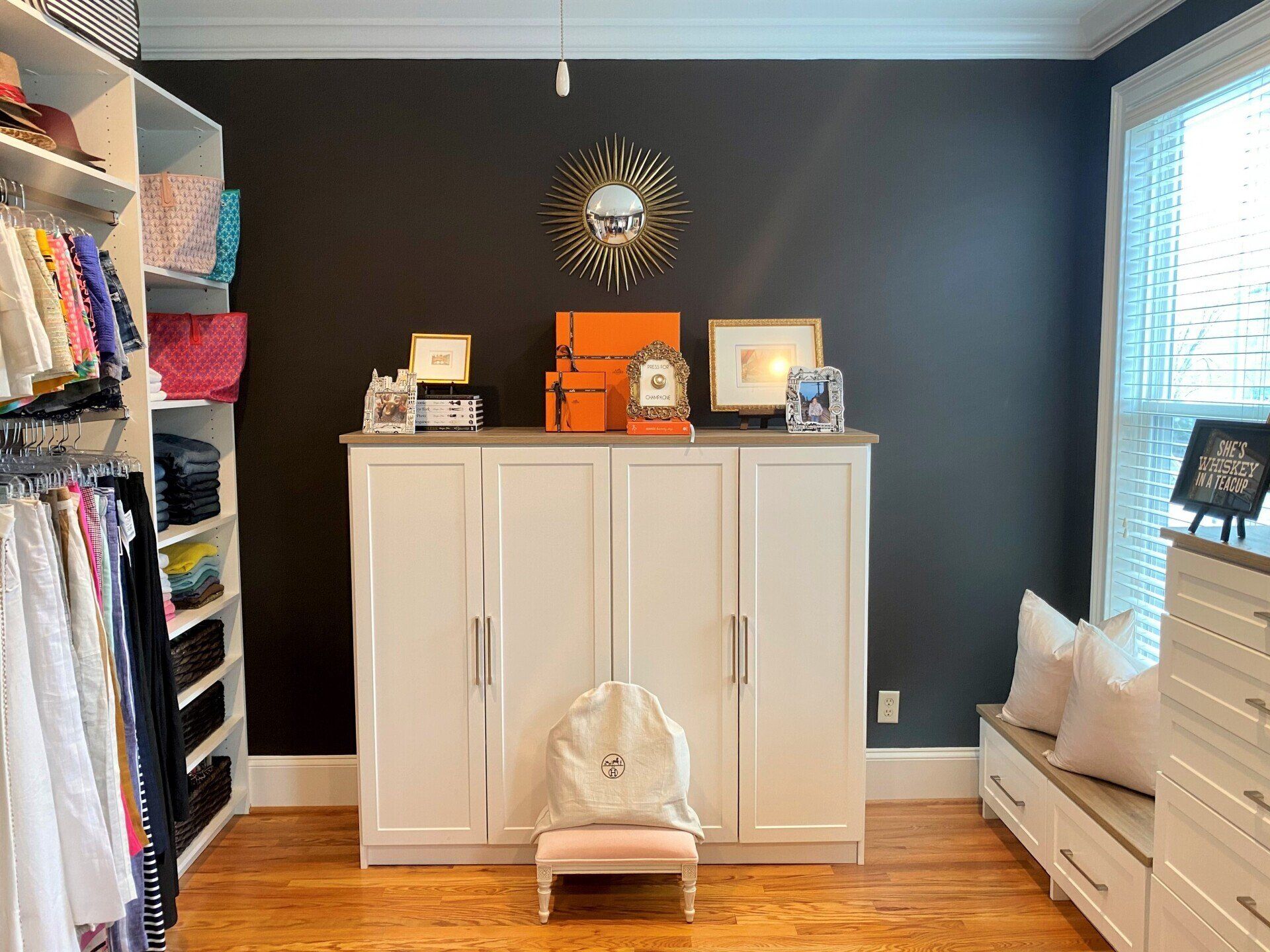 A walk in closet with black walls and white cabinets.