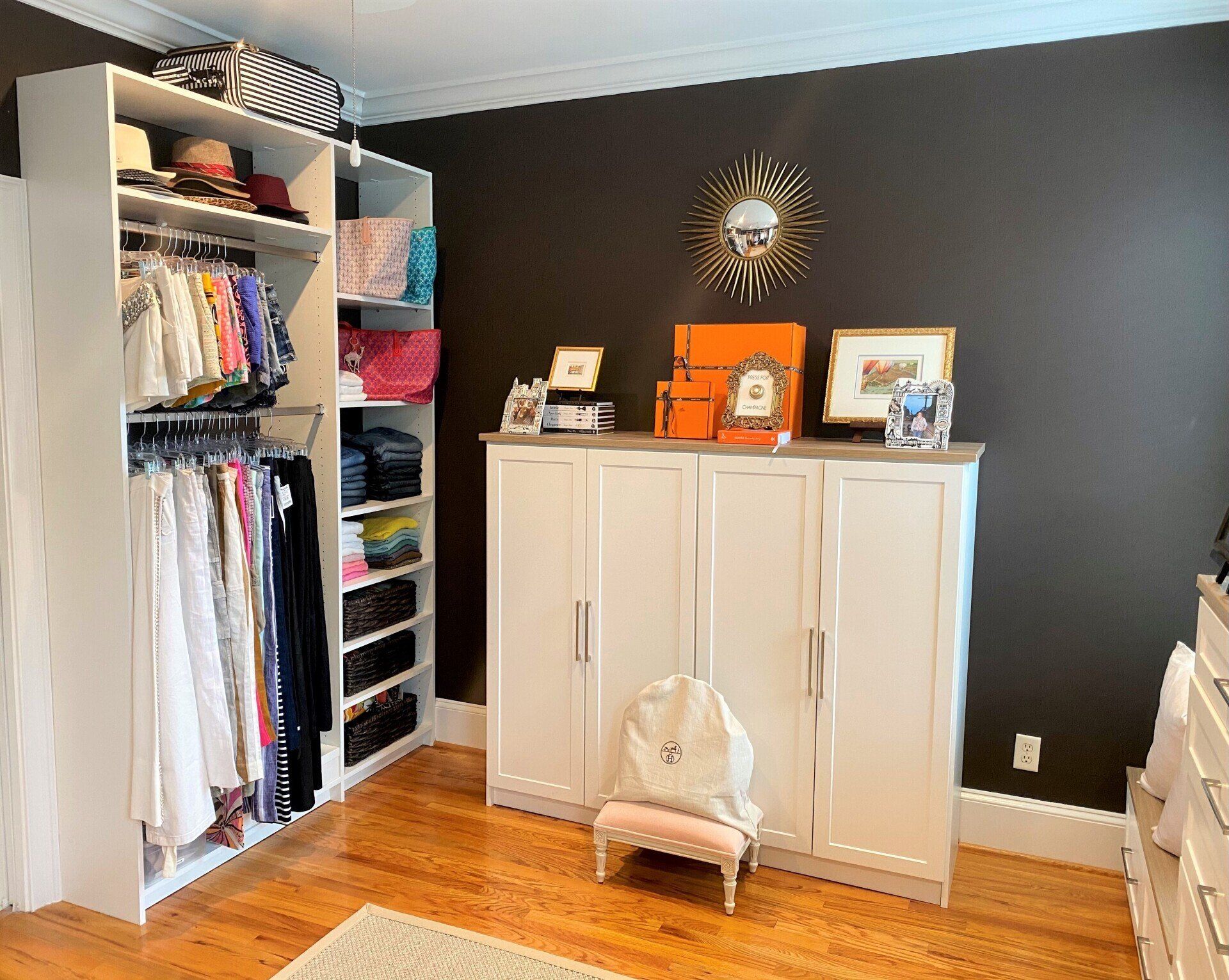 A walk in closet with lots of clothes and a chair.