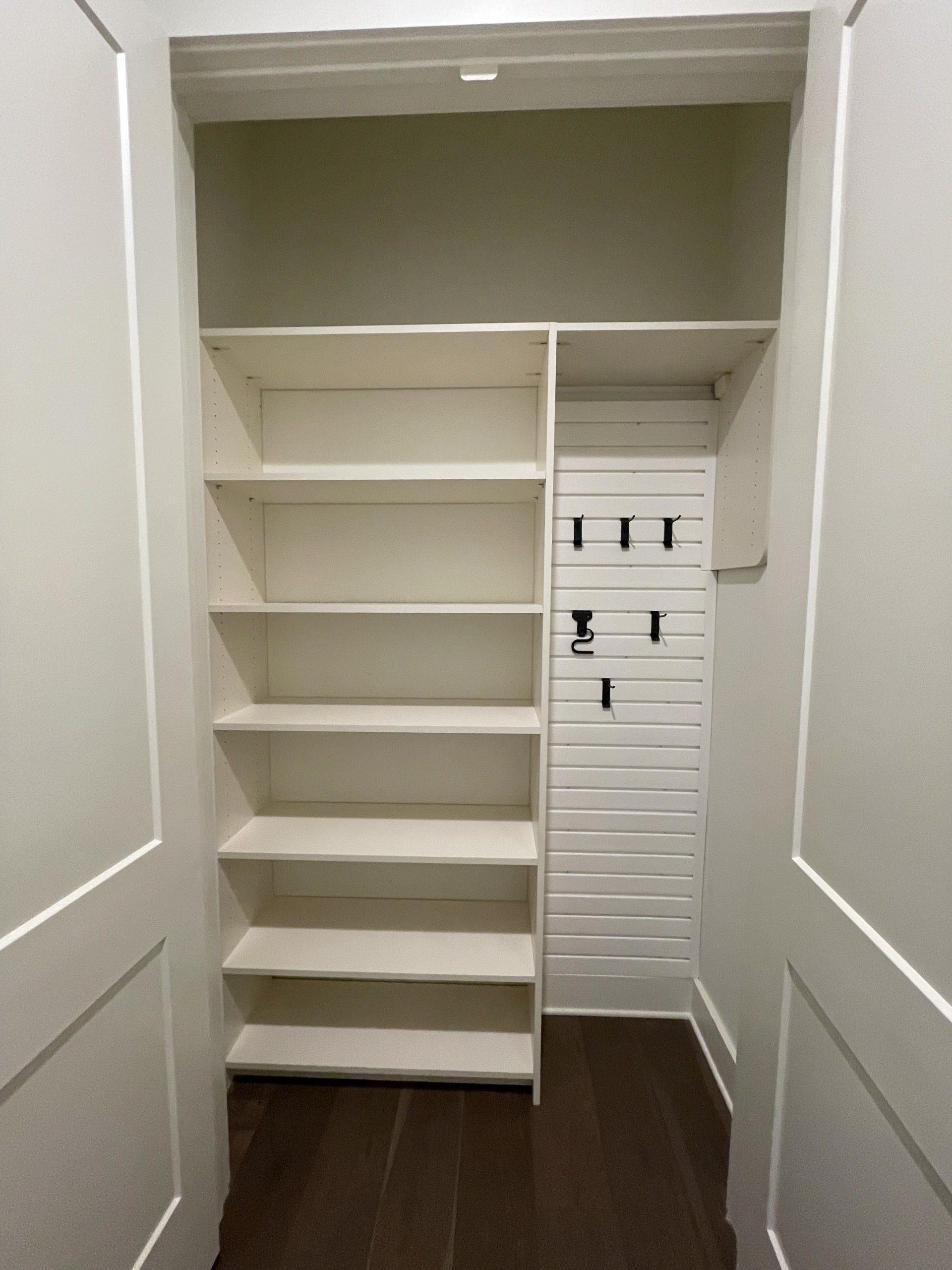 A closet with a lot of shelves and hooks on the wall.
