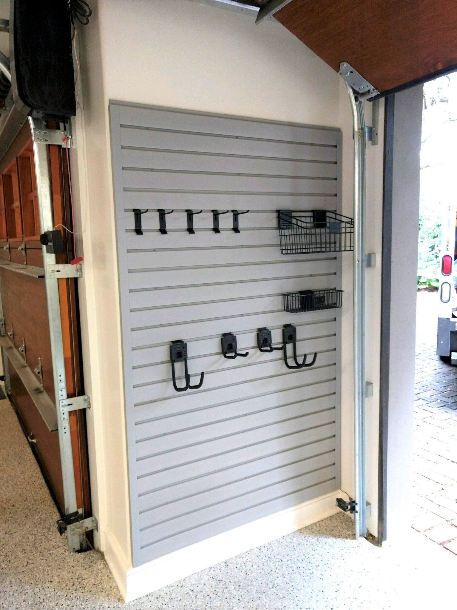 A garage door with a slat wall and hooks on it.
