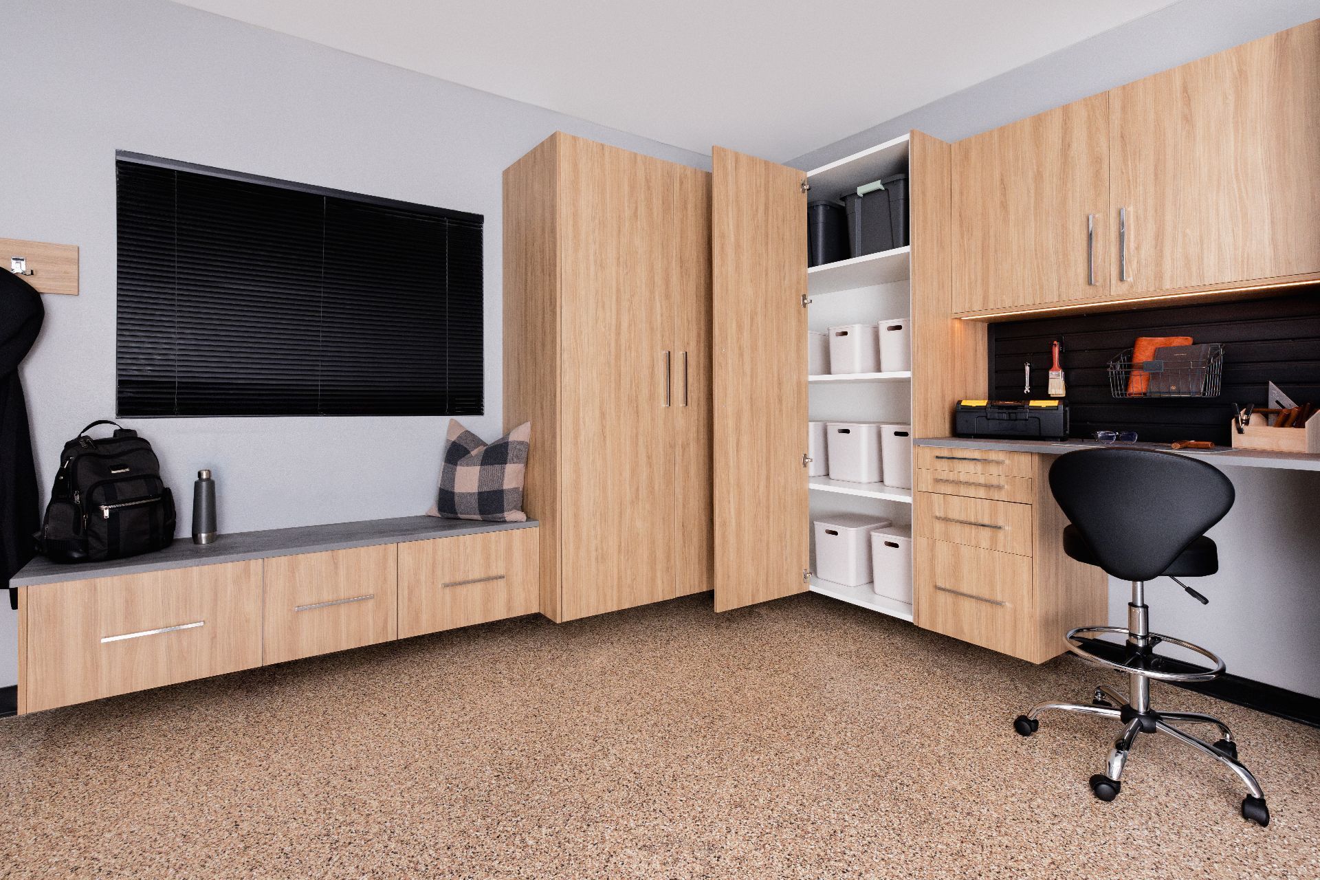 Home office with wood cabinets, desk, wall-mounted TV, and black office chair on beige carpet.