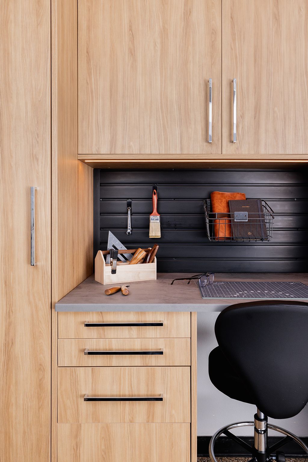 Wooden desk nook with shelves, tools, and a black chair