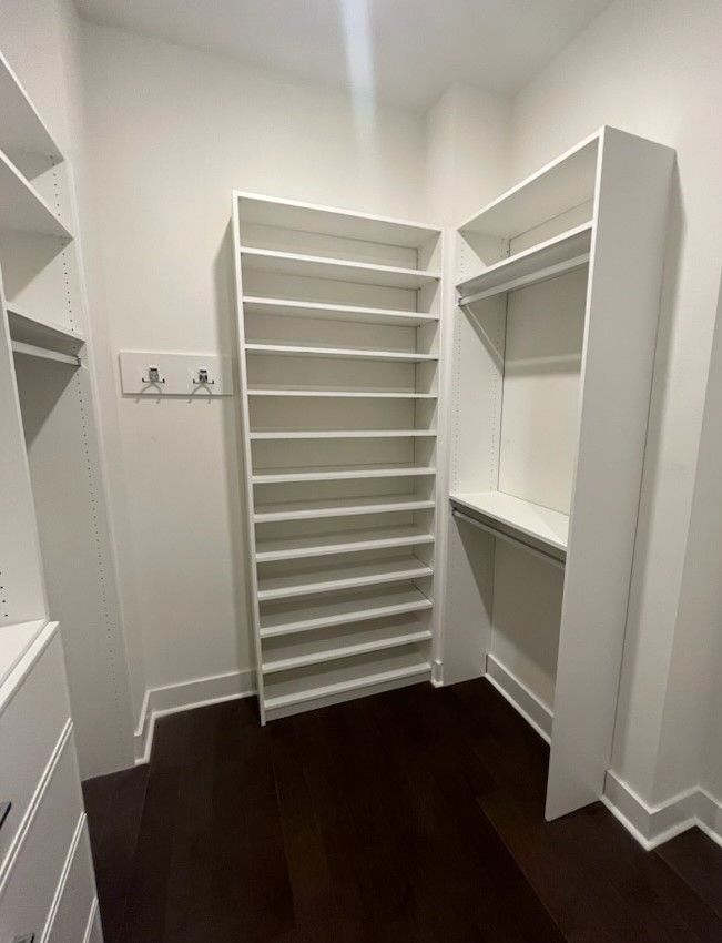 A walk in closet with lots of shelves and a wooden floor.