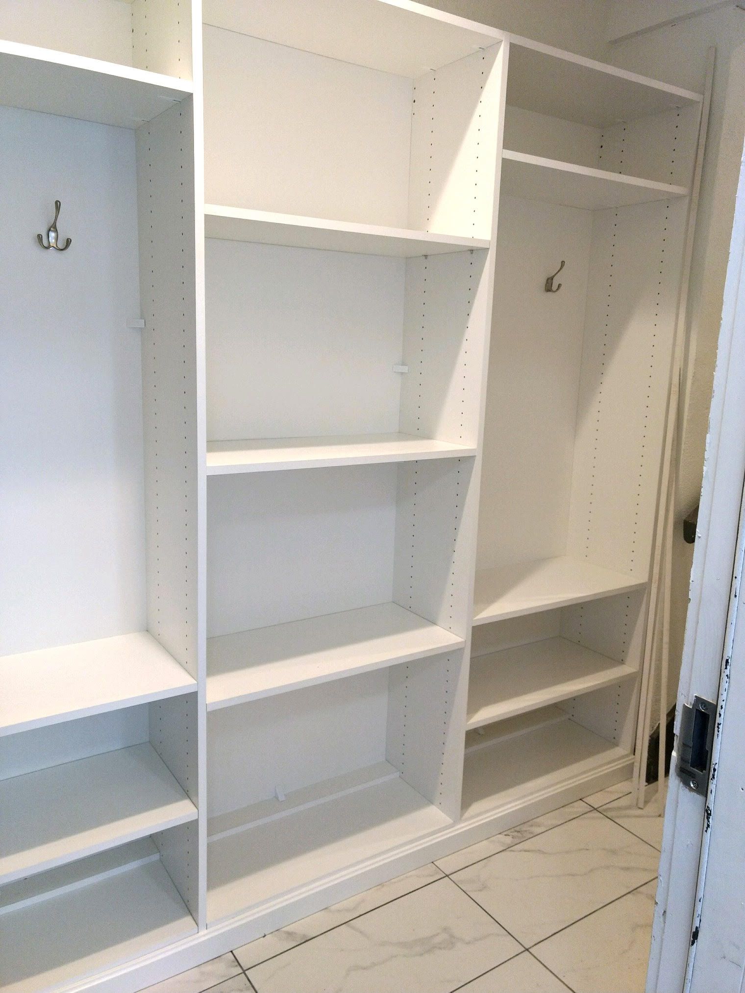 A closet with lots of shelves and hooks on the wall.