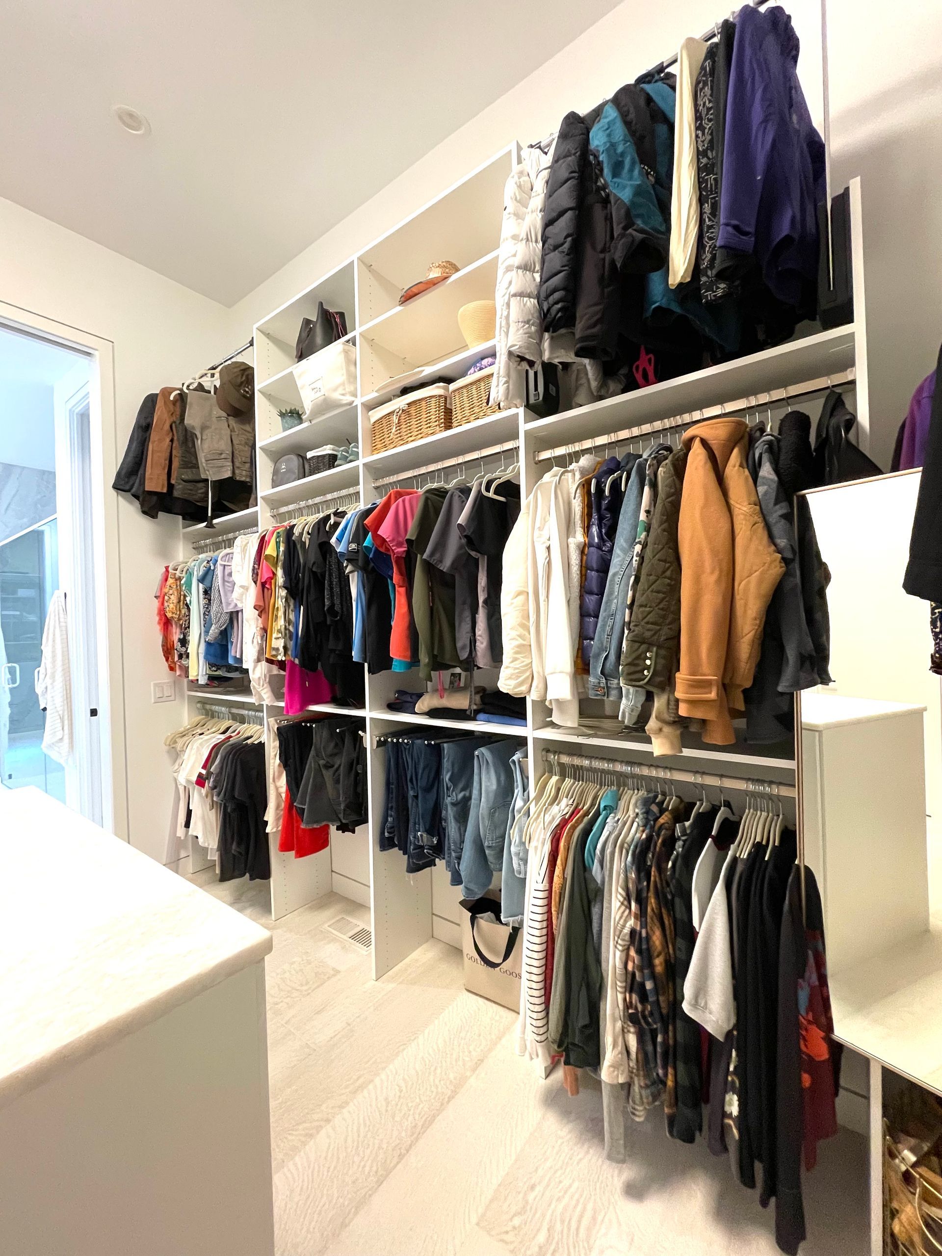 A walk in closet filled with lots of clothes and shoes.