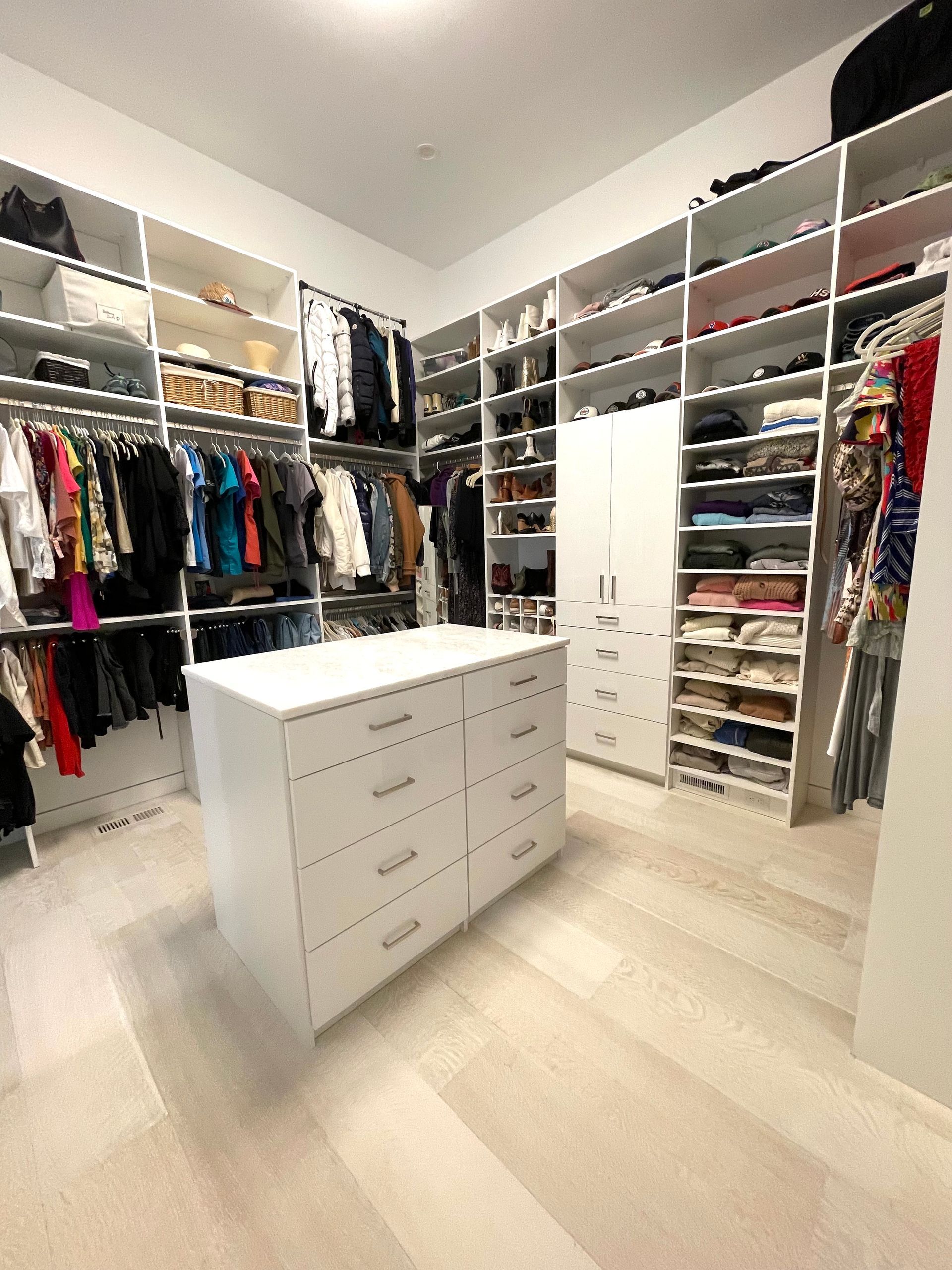 A walk in closet filled with lots of clothes and a large island.