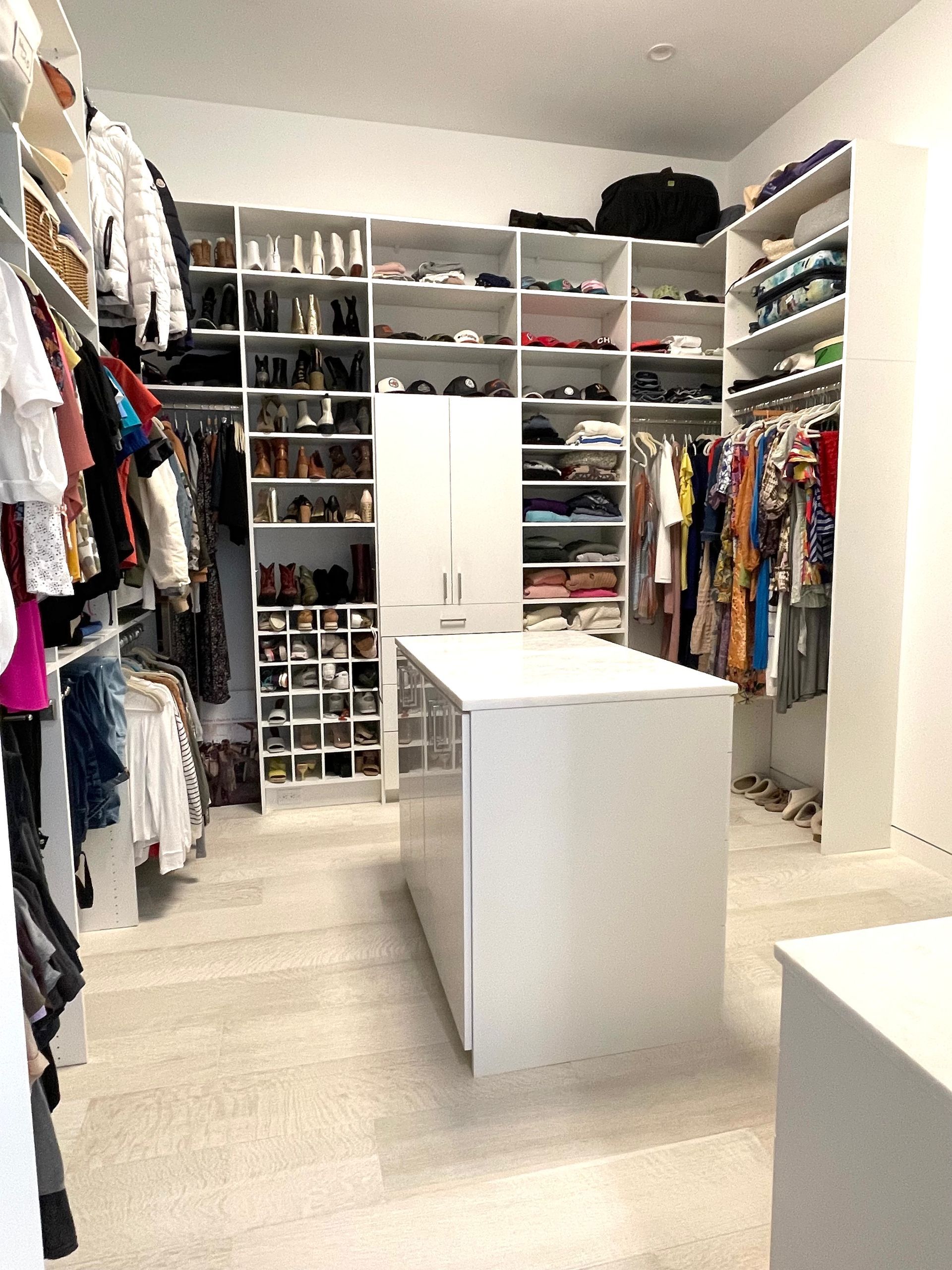 A large walk in closet filled with lots of clothes and shoes.
