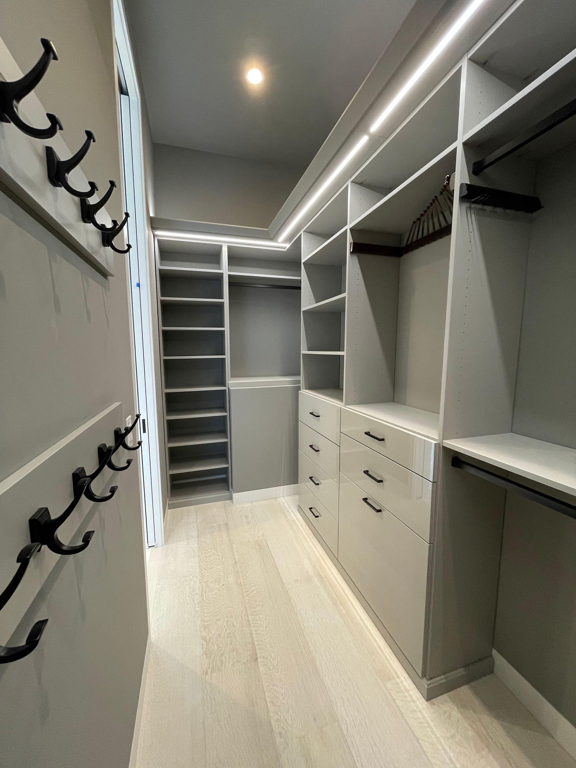 A walk in closet with lots of shelves and hooks