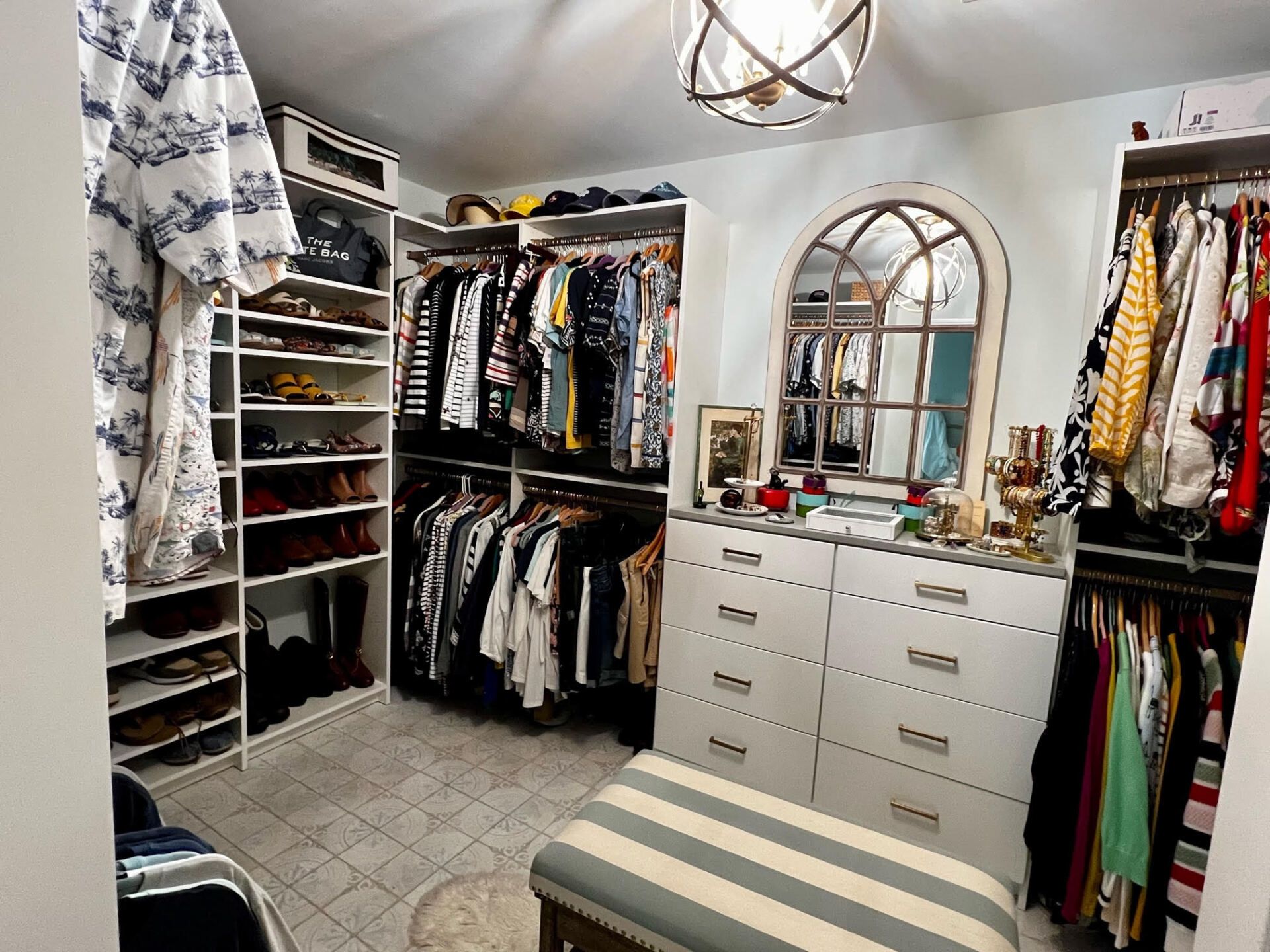 A walk in closet filled with lots of clothes and a bench.