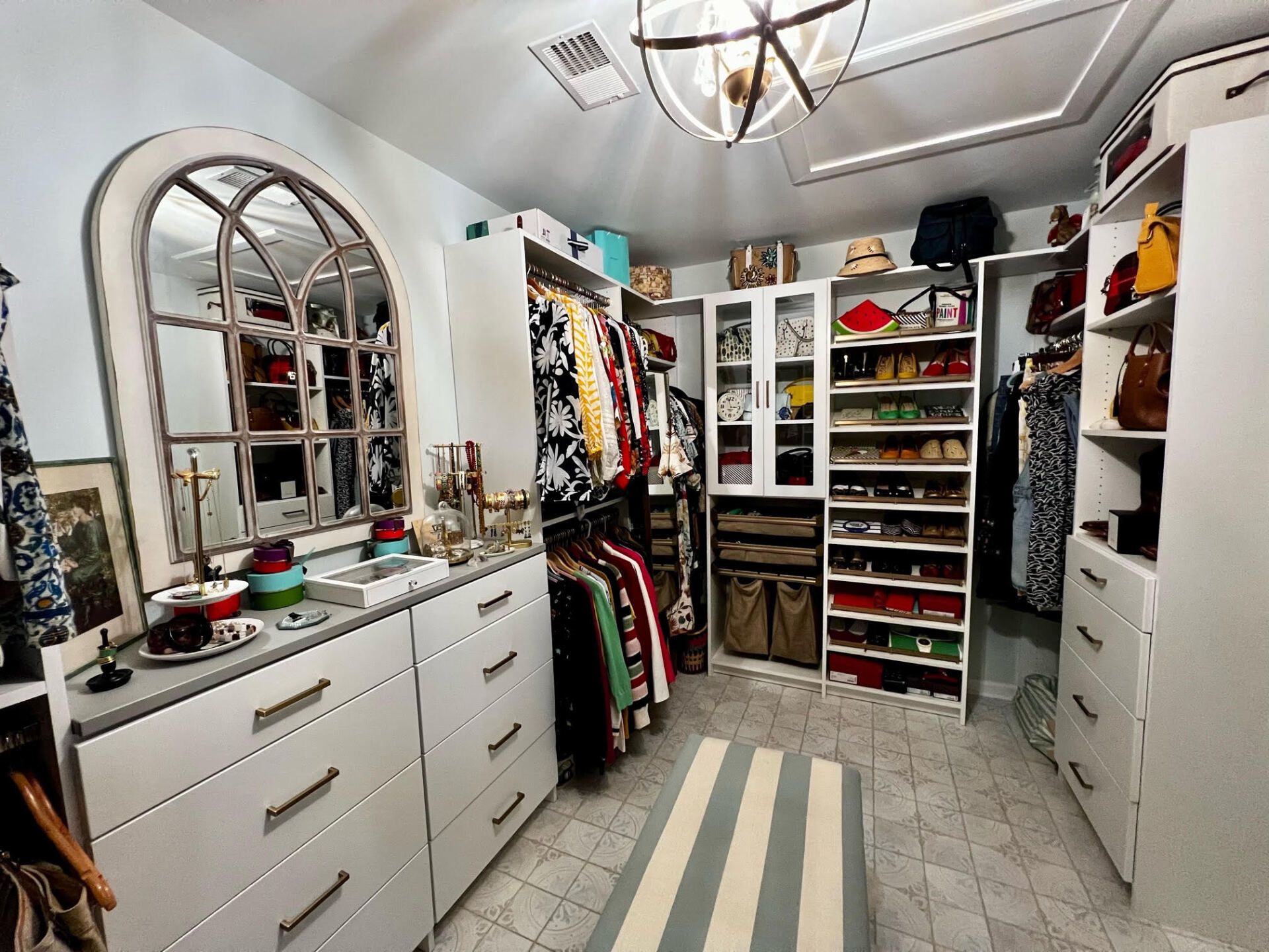 A walk in closet filled with lots of clothes and a mirror.