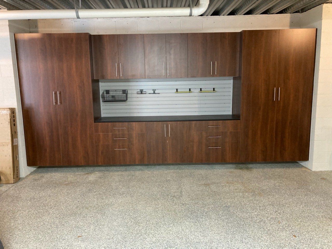A garage with a lot of cabinets and a slat wall.