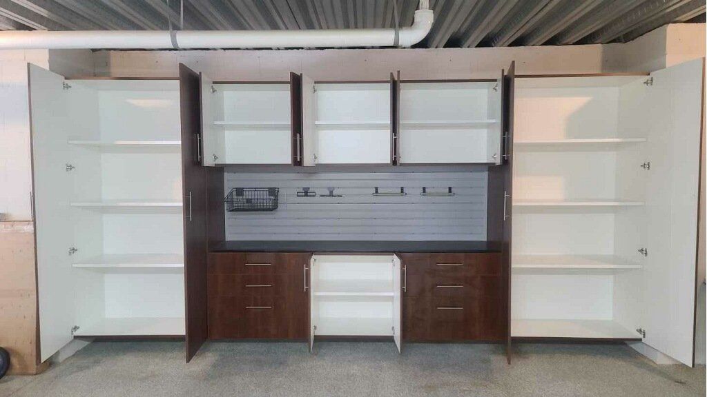 A wall of cabinets with the doors open in a garage