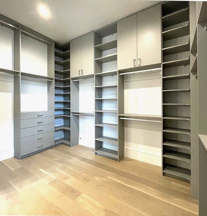 A walk in closet with lots of shelves and cabinets.